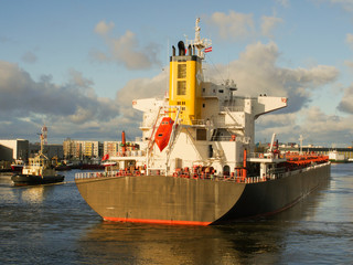 Tugboat assisting bulk cargo ship to leave port