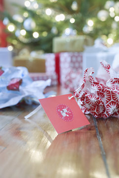 Unwrapped Gift Paper And Tag On Hardwood Floor With Christmas Tree In Background