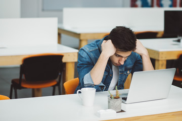 Serious young guy with beard working on laptop