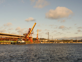 Fototapeta premium Tug vessel in the port, industrial background. Marine landscape
