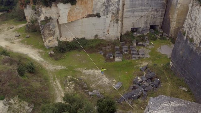AERIAL: Brave young man slacklining on challenging highline over deep abyss 