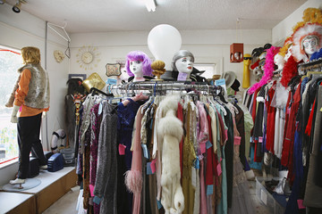 View of clothing and wigs in a crowded second hand store