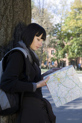 Young woman in winter clothes reading map at a park