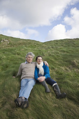Full length of a middle aged couple sitting on coastal landscape