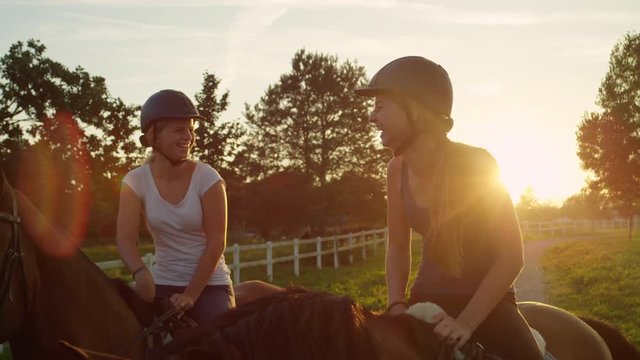 SLOW MOTION: Two happy beautiful young girls enjoying horse ride at sunset