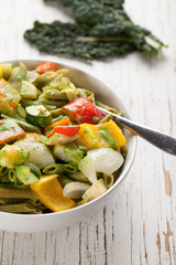 Large white porcelain bowl of pasta and roasted vegetables with a creamy kale sauce cropped shot on white