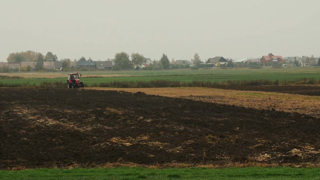 Farmer plowing the field. Small scale farming with tractor and plow in field, Cultivating tractor in the field.