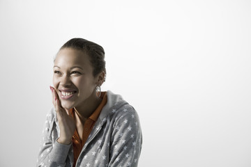 Fototapeta premium Smiling young woman touching her cheek against gray background