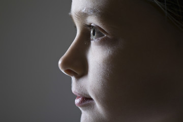 Closeup side view of a young girl against gray background