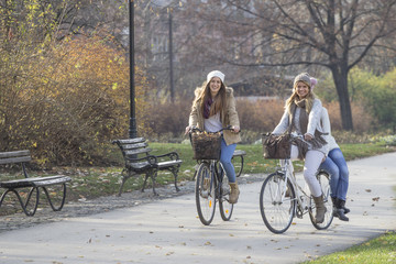 Obraz premium Three girls ride bicycles in park