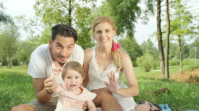 CLOSE UP: Happy parents with beautiful baby girl sitting on blanket in park