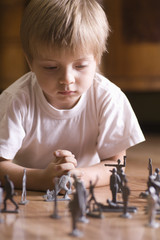 Closeup of a young boy playing with toy soldiers on floor