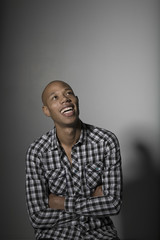Fototapeta premium young African American man smiling while looking up against gray background