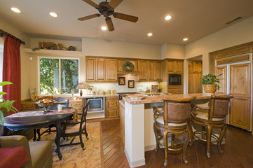 View of spacious kitchen with stools at counter and dining area in house