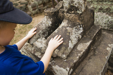 Young boy touching feet of ancient statue