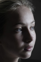 Fototapeta premium Closeup of a teenage girl looking away against black background