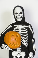 Portrait of a kid dressed in skeleton costume holding Jack-O-Lantern isolated over white background