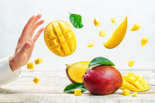 Male hand with mango and mangoes flying slices