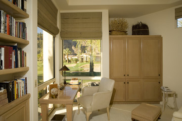 View of bookshelf by chair and table in study room