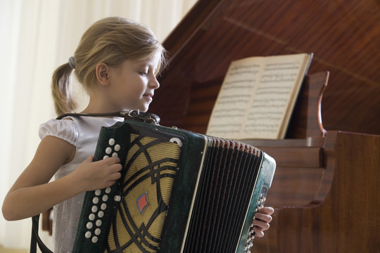 Side view of a young girl playing the accordion