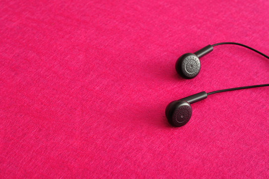 Earphones isolated against a pink background
