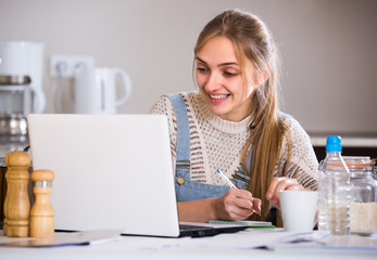 Woman working online at home kitchen .