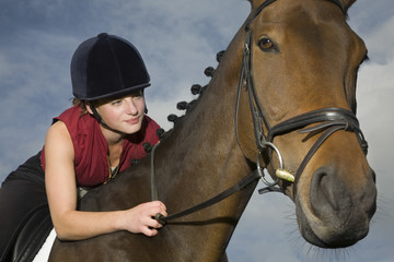 Closeup of a female horseback rider sitting on a brown horse