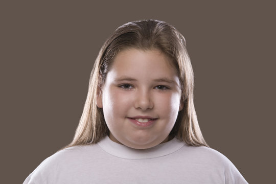 Closeup of an overweight girl smiling against gray background