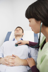 Obraz premium Female doctor examining a male patient with stethoscope in the clinic