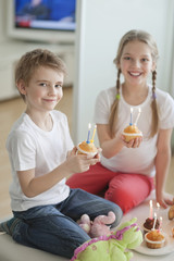 Obraz na płótnie Canvas Portrait of siblings celebrating birthday with cup cakes
