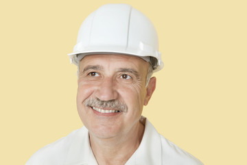 Happy senior man with hardhat over yellow background