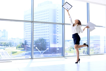 Fototapeta na wymiar Happy modern business woman with financial report is running in office hall