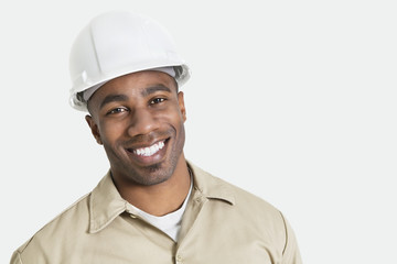 Portrait of happy African construction over with hardhat over gray background