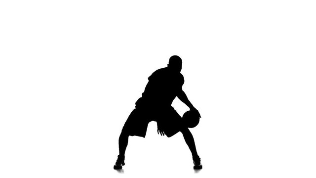 Basketball player fills the ball. Slow motion. Silhouette. White background