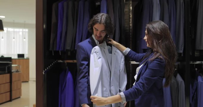 Business Man Fashion Shop, Customer Choosing Suit Clothes In Retail Store, Shopping Seller Woman Show Formal Wear Slow Motion 60 Fps