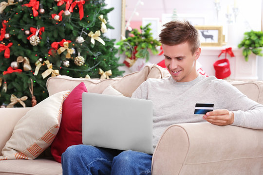 Young Man Shopping Online With Credit Card At Home For Christmas