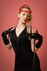 Pretty actress in black retro dress singing with microphone