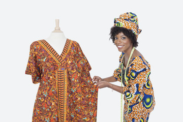 Fototapeta premium Portrait of an African American female fashion designer working on dashiki over gray background