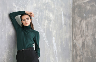 Obraz premium Beautiful woman in fashion clothes on grunge wall background