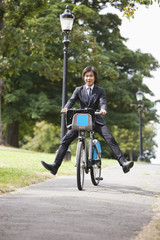 Fototapeta premium Portrait of young businessman riding bicycle with legs kicked out