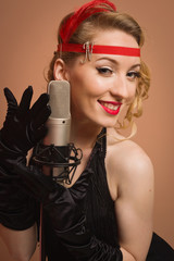Pretty actress in black retro dress singing with microphone