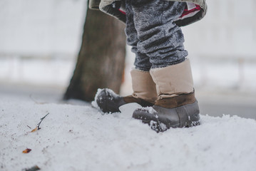 Ноги в сапогах на снегу зимой, маленький ребёнок