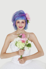 Portrait of beautiful young woman in wedding dress with dyed hair against gray background
