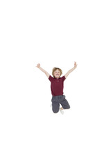 Portrait of elementary boy jumping in air with arms raised over white background