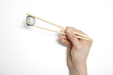 Man's hand holding sushi roll in chopsticks against white background