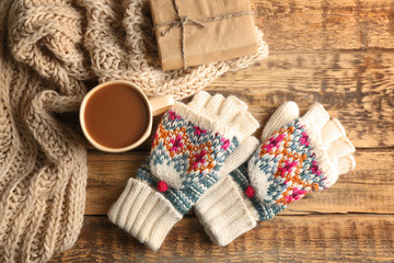 Knitwear and cup of coffee on wooden background