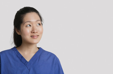 Fototapeta premium Young Asian female doctor looking up over gray background