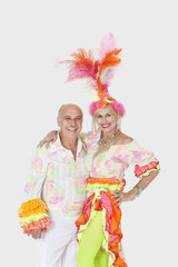 Portrait of happy senior dance couple in Brazilian outfits over gray background