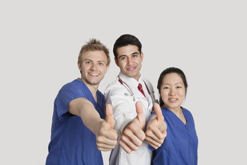 Fototapeta premium Portrait of a happy medical team gesturing thumbs up over gray background