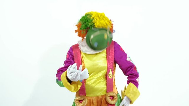 Colorful circus clown in green hat playing with toy-fish skeleton